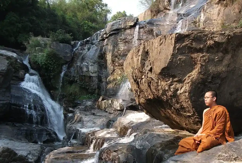 Şelale kenarında meditasyon yapan Budist rahip. Meditasyon ve Tapınma Ritüelleri için harika bir mekan.